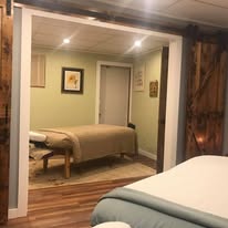 Hallway perspective showing two open treatment rooms with barn wood accents and warm lighting at Hands On Health