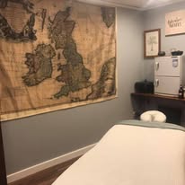 Treatment room with vintage British Isles map on wall and clean white towel roll on massage table