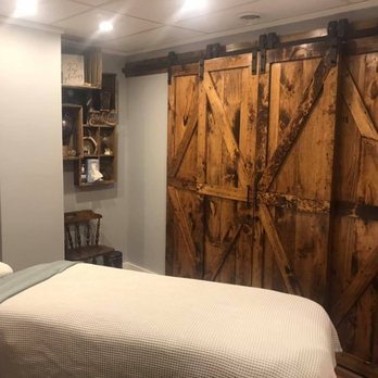 Treatment room with signature rustic barn doors as accent wall and massage table with white linens